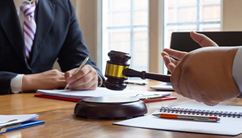 Attorney meeting with a client across a desk with a gavel and documents.